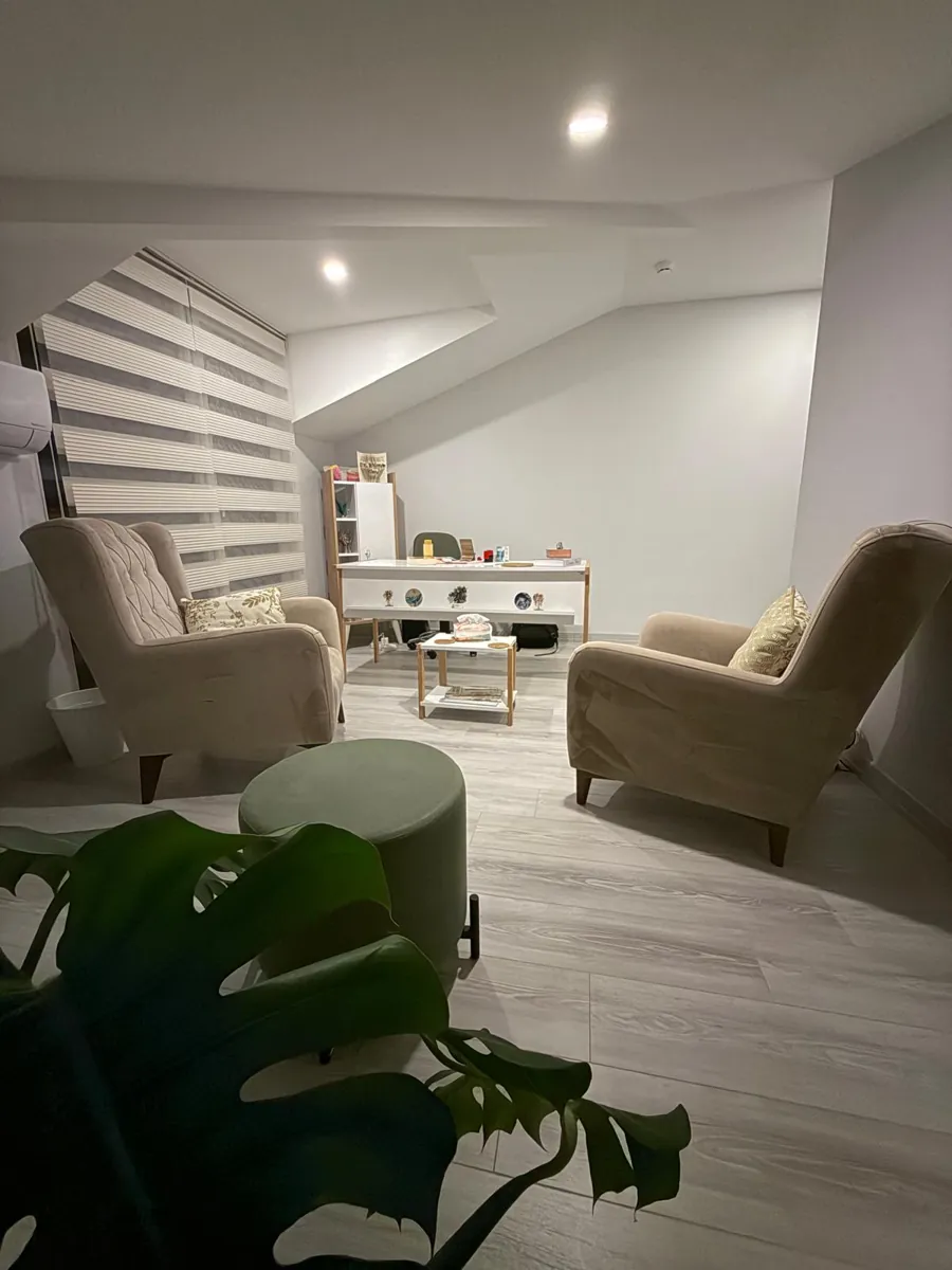 Görüşme odasında karşılıklı koltuklar ve pencere önündeki çalışma masası